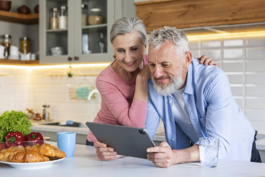 A senior couple looking at a tablet together in their kitchen.